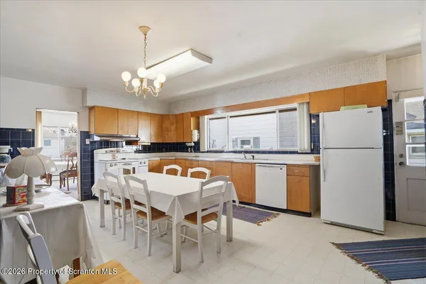 a kitchen with stainless steel appliances granite countertop a refrigerator a sink dishwasher a stove and a dining table with wooden floor