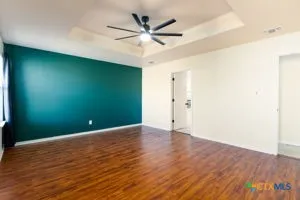 an empty room with wooden floor and a ceiling fan