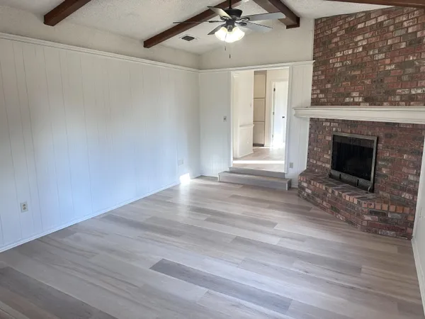 an empty room with wooden floor fireplace and windows