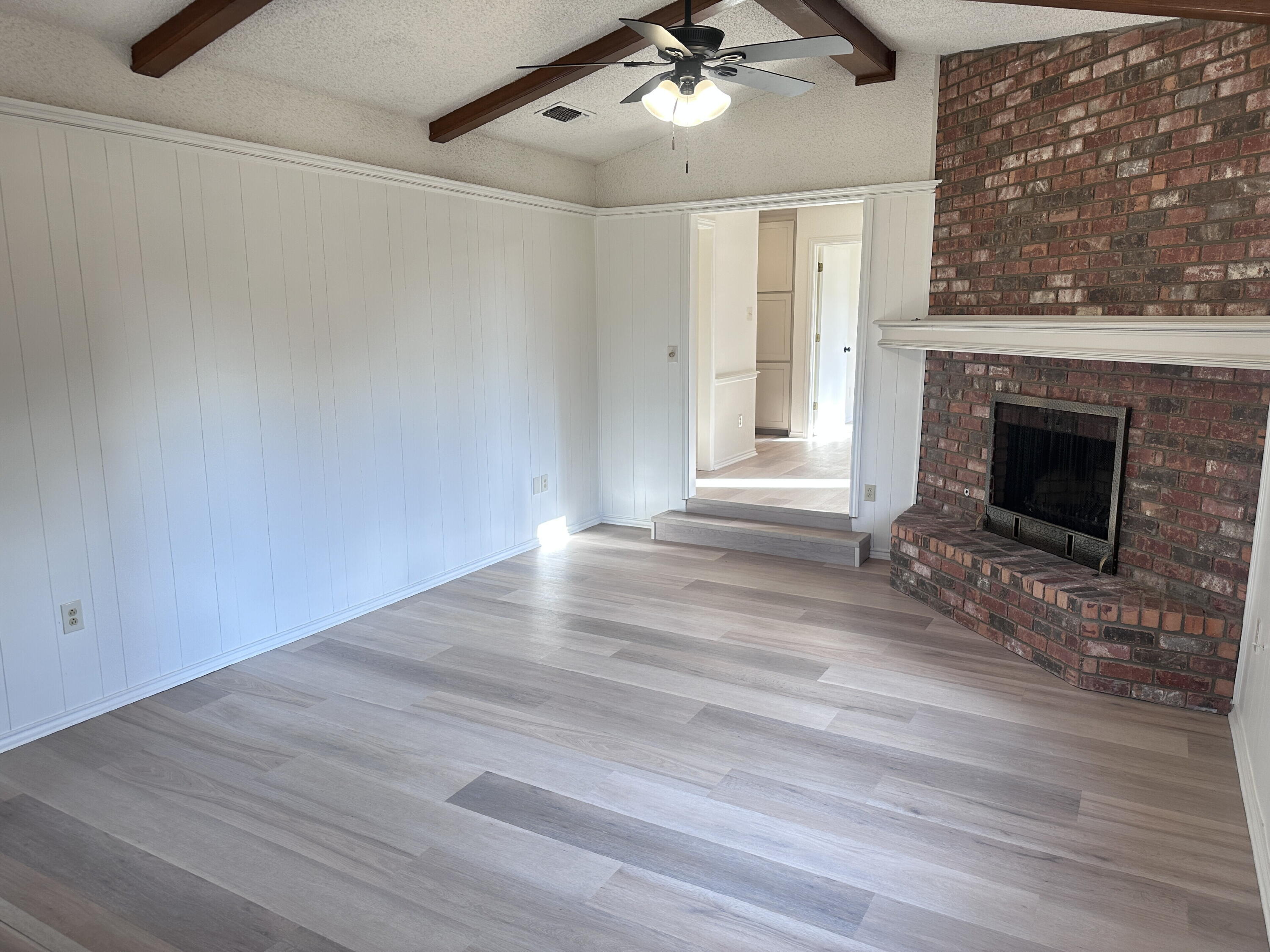 2217 33rd Street, Unit B Lubbock, TX 79411 - Photo 2 of 14 an empty room with wooden floor fireplace and windows