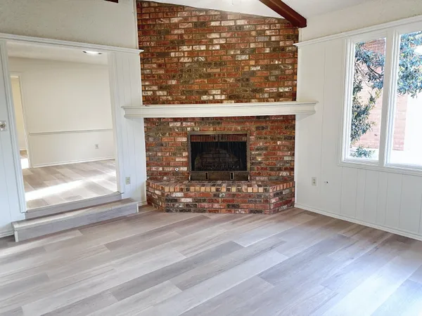 an empty room with wooden floor a fireplace and windows
