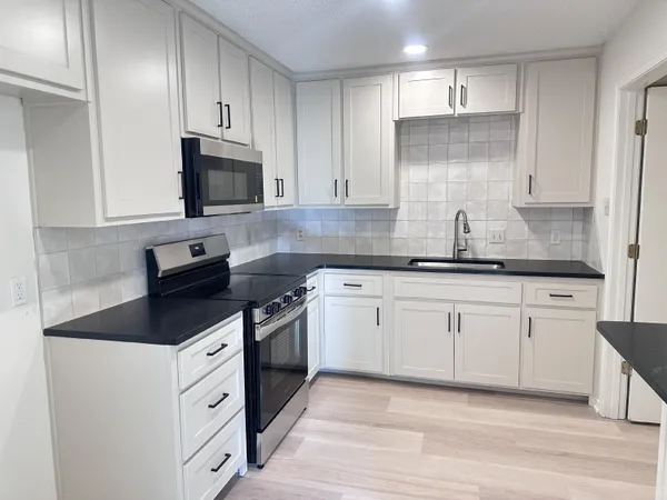 a kitchen with granite countertop a sink a stove and cabinets