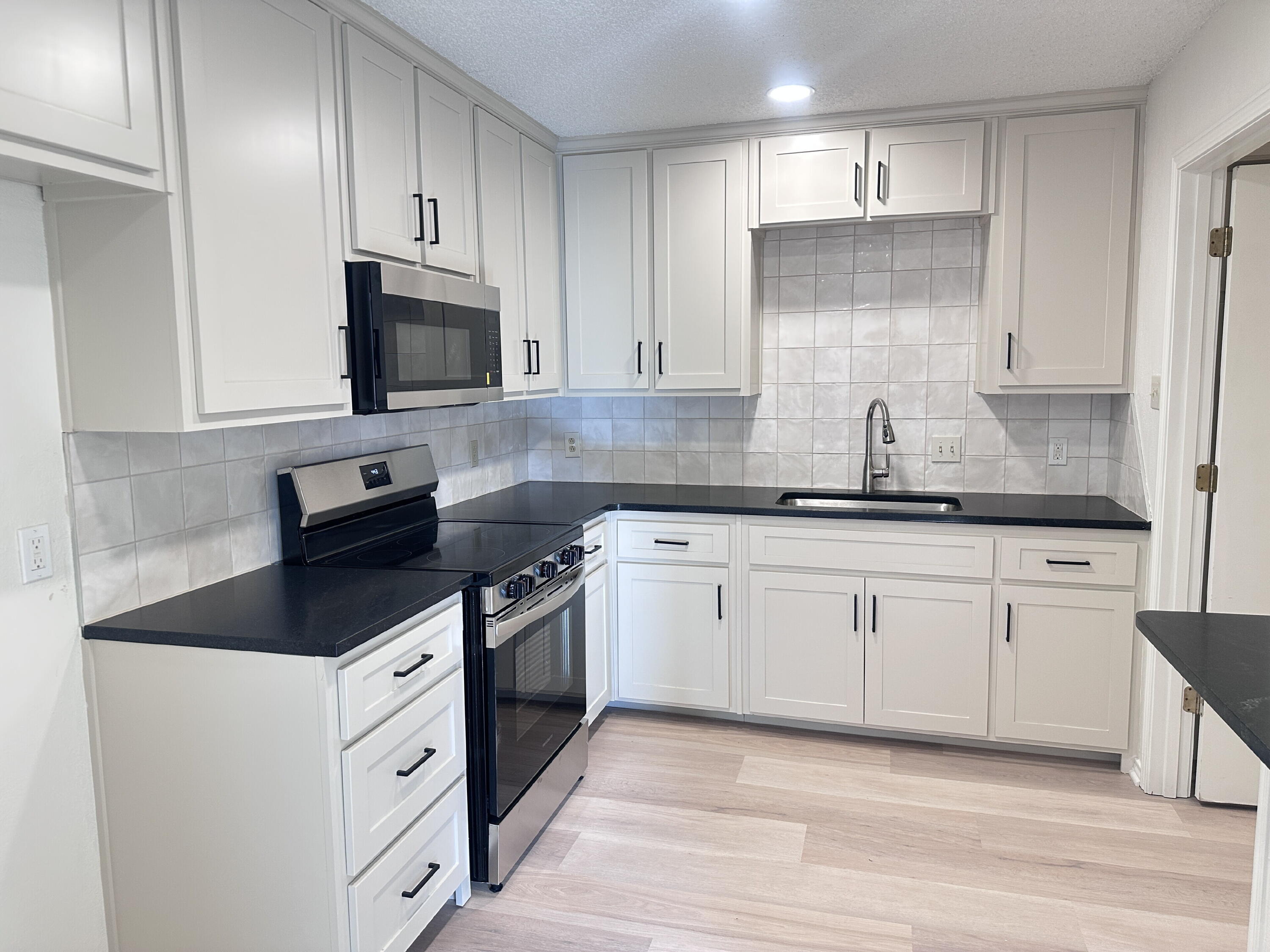 2217 33rd Street, Unit B Lubbock, TX 79411 - Photo 6 of 14 a kitchen with granite countertop a sink a stove and cabinets