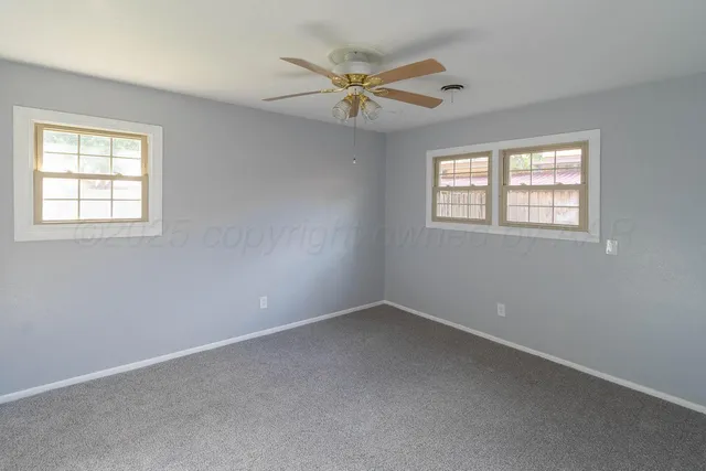 an empty room with windows and fan