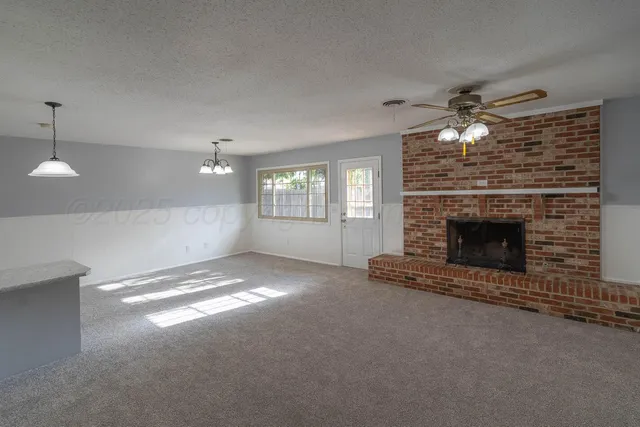 a view of an empty room with a fireplace and a window