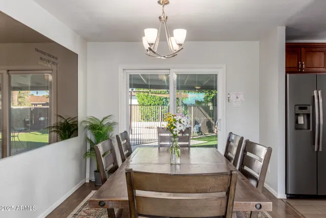 a dining room with wooden floor a chandelier a glass table and chairs