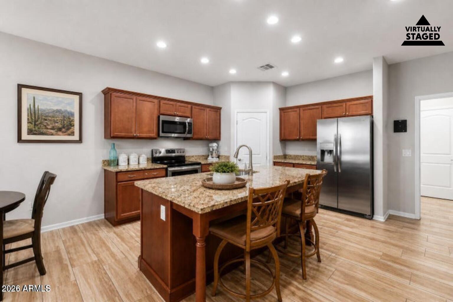 614 North Tomahawk Road Apache Junction, AZ 85119 - Photo 10 of 44 a kitchen with stainless steel appliances granite countertop a stove a refrigerator a microwave a sink a dining table and chairs with wooden floor