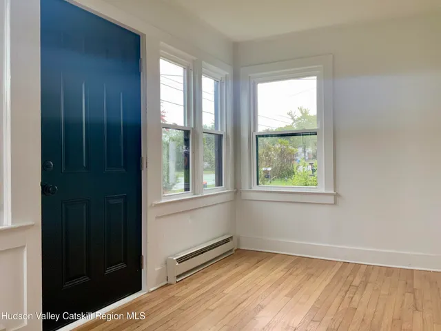 a view of an empty room with a window and wooden floor