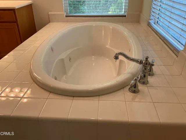 a spacious bathroom with a granite countertop sink a large mirror and cabinets