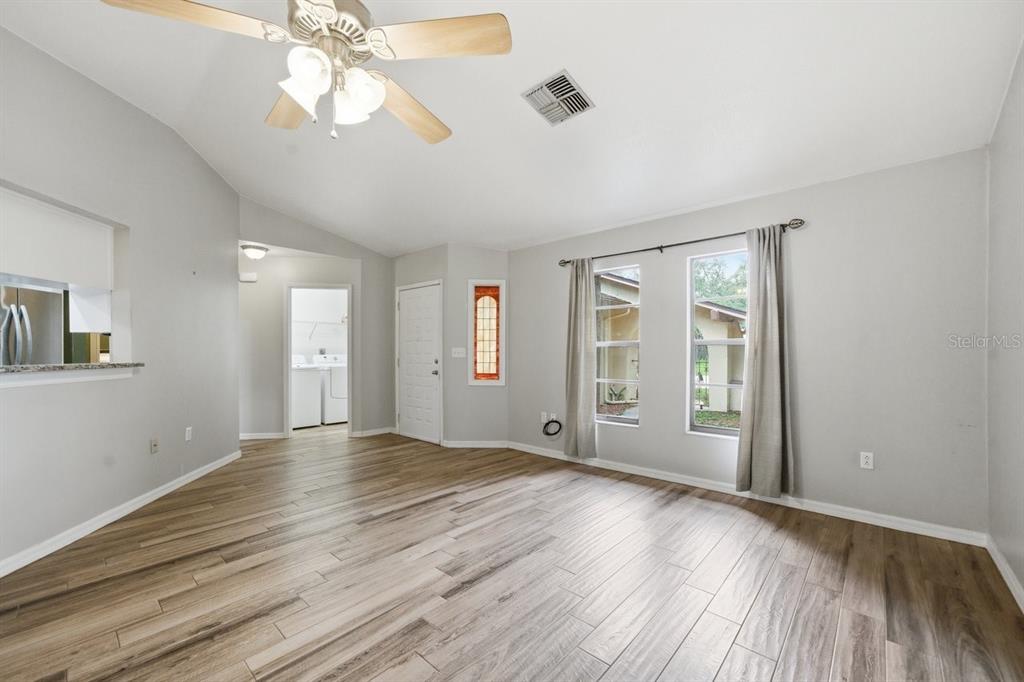 8316 Kingsdale Street Spring Hill, FL 34608 - Photo 5 of 30 an empty room with wooden floor chandelier fan and windows