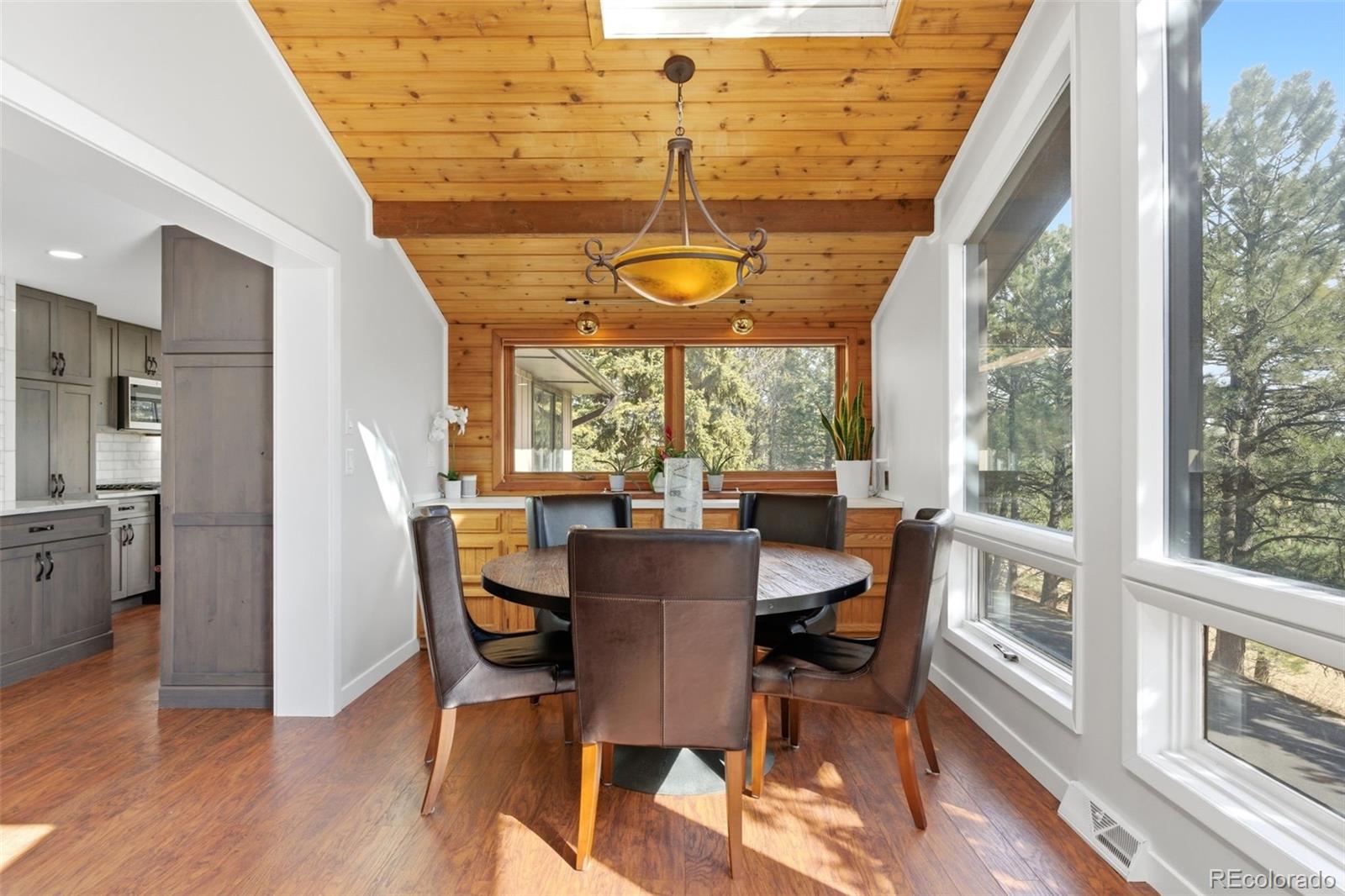 3155 Chestnut Circle Evergreen, CO 80439 - Photo 14 of 50 a dining room with wooden floor a chandelier a glass table and chairs