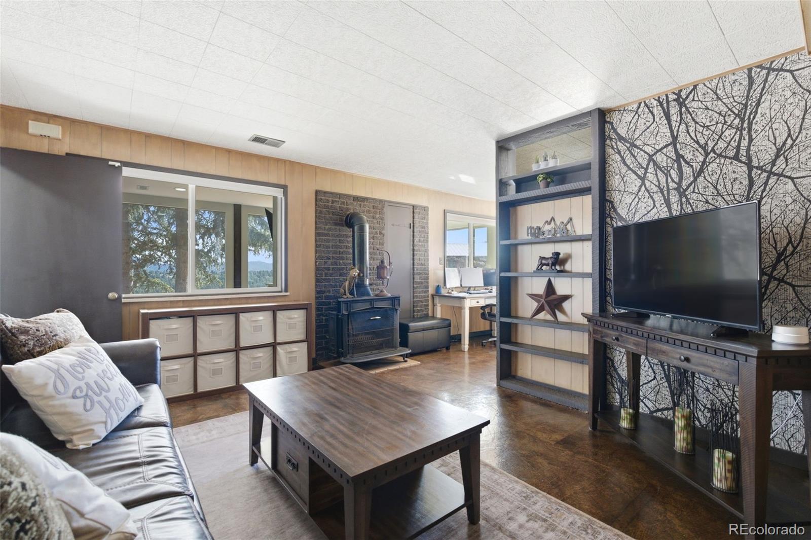 3155 Chestnut Circle Evergreen, CO 80439 - Photo 40 of 50 a living room with furniture a flat screen tv and a floor to ceiling window