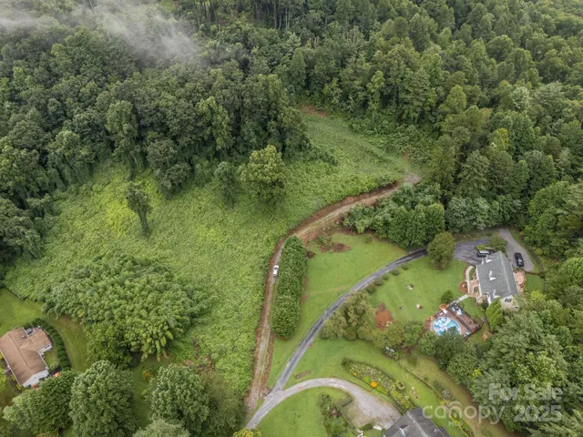 an aerial view of residential houses with outdoor space and trees