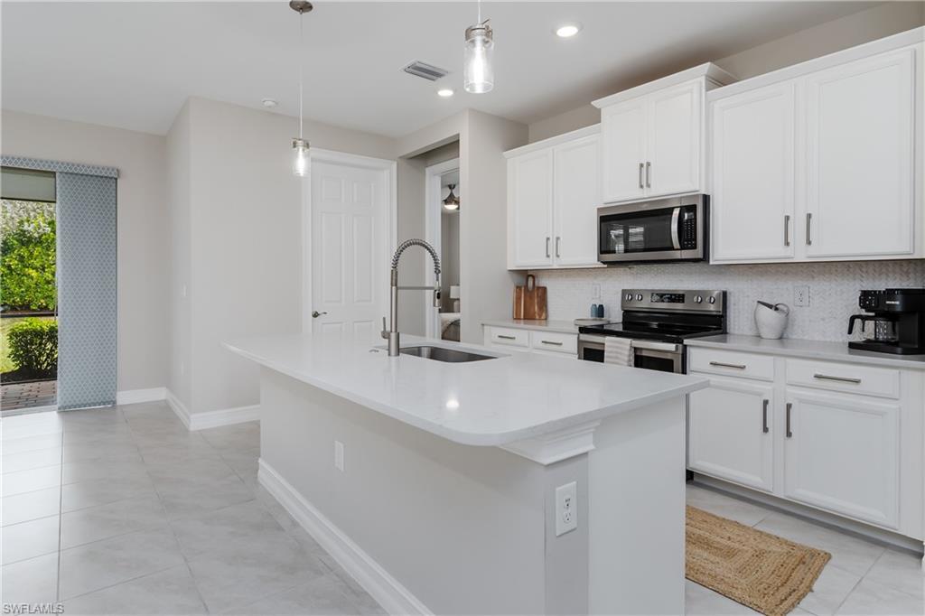 14643 Stillwater Way Naples, FL 34114 - Photo 11 of 50 a kitchen with kitchen island a sink stainless steel appliances and cabinets