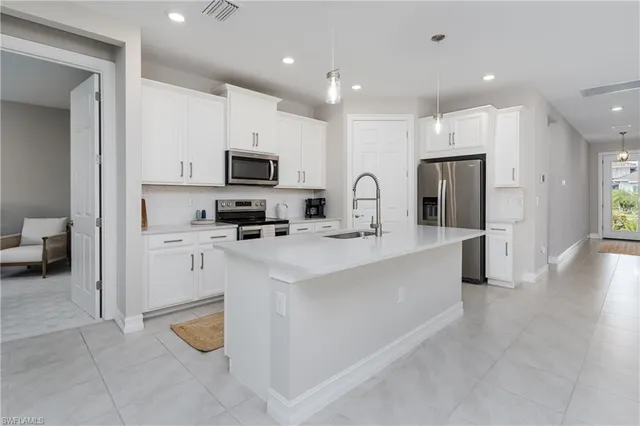 a large white kitchen with a refrigerator a stove top oven a sink and cabinets