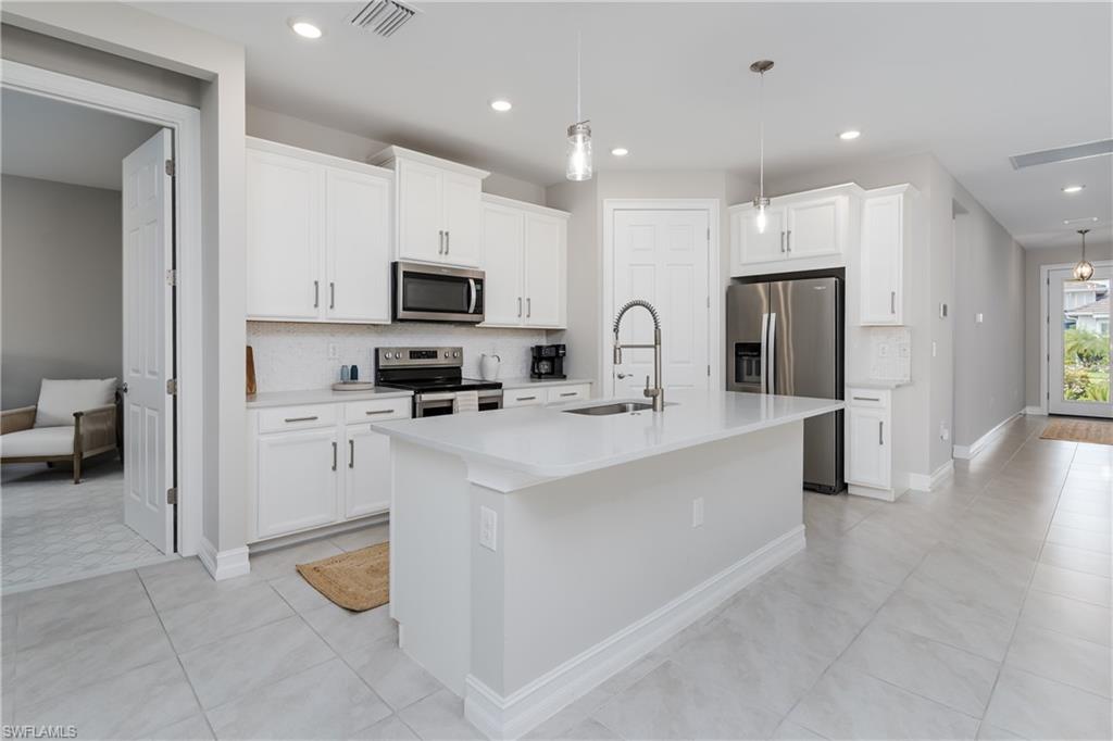 14643 Stillwater Way Naples, FL 34114 - Photo 10 of 50 a large white kitchen with a refrigerator a stove top oven a sink and cabinets