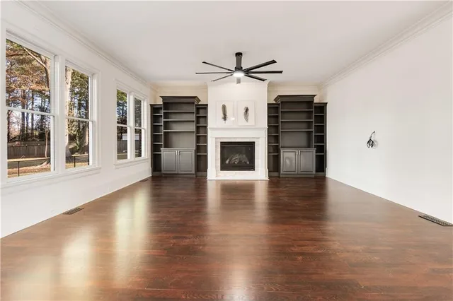an empty room with wooden floor fireplace and windows