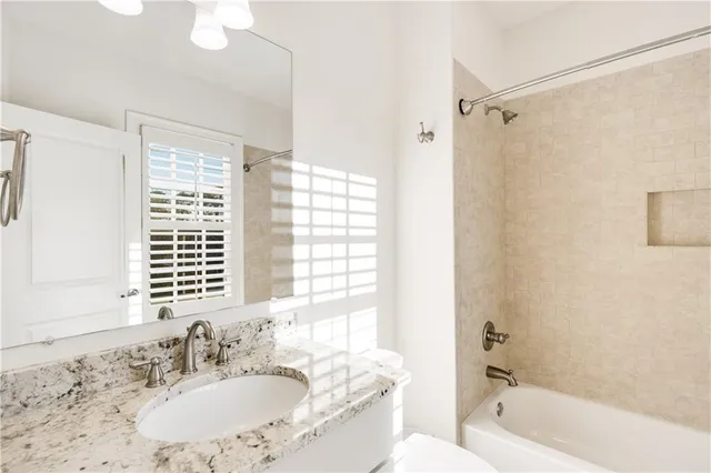 a bathroom with a granite countertop sink a mirror a bathtub and shower