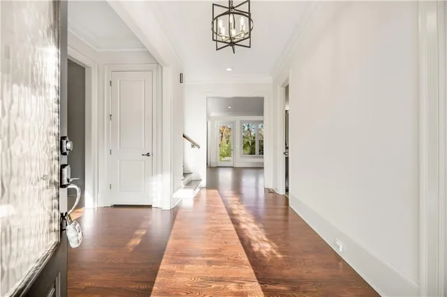 a view of a hallway with wooden floor and a chandelier