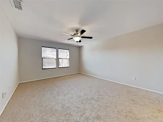 an empty room with windows and ceiling fan