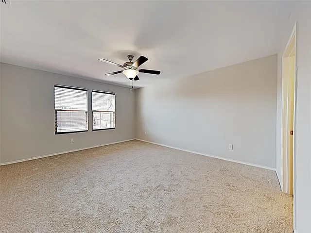 an empty room with windows and ceiling fan view