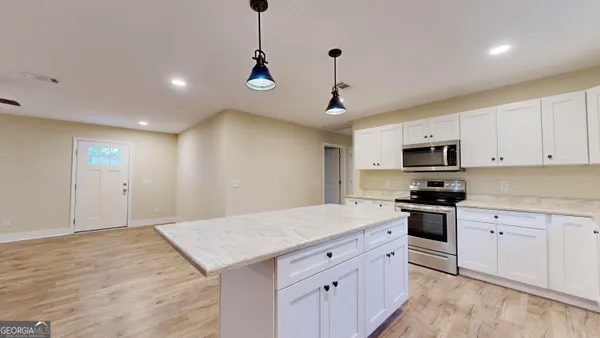 a kitchen with stainless steel appliances granite countertop a sink a stove a refrigerator and white cabinets