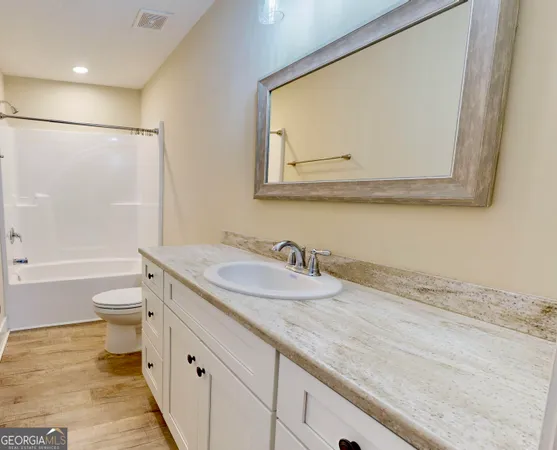 a bathroom with a granite countertop sink mirror vanity and toilet