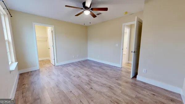 a view of empty room with wooden floor and fan