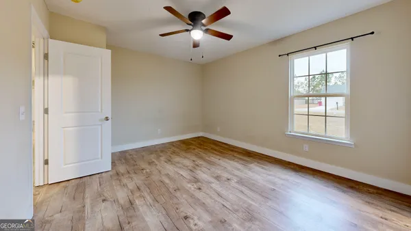 a view of empty room with wooden floor and fan