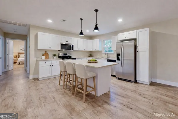 a kitchen with stainless steel appliances kitchen island granite countertop a refrigerator a stove a sink a microwave and white cabinets with wooden floor