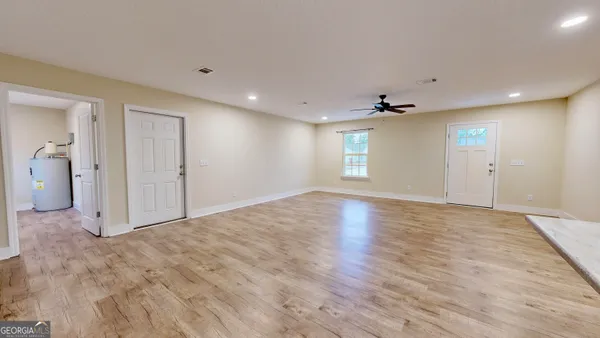 a view of empty room with wooden floor and fan