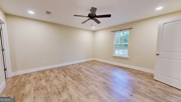 an empty room with wooden floor and windows