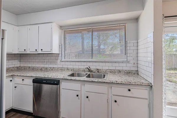 a kitchen with granite countertop white cabinets and a sink