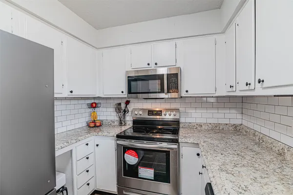 a kitchen with granite countertop white cabinets and stainless steel appliances