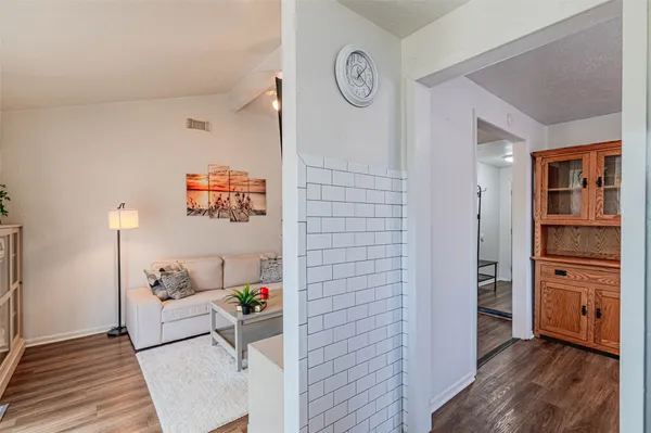 a view of a hallway to room with wooden floor and closet