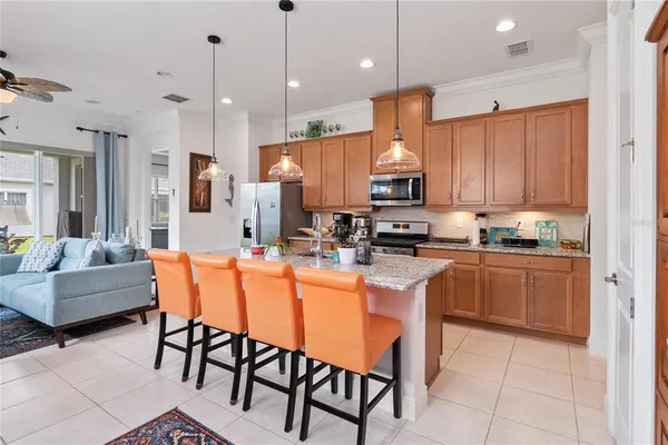 a kitchen with stainless steel appliances granite countertop a stove a sink a microwave a refrigerator and chairs