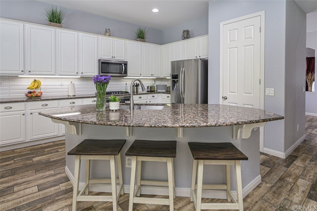 33915 Pinehurst Drive Yucaipa, CA 92399 - Photo 9 of 33 a kitchen with stainless steel appliances granite countertop a table chairs stove refrigerator and cabinets