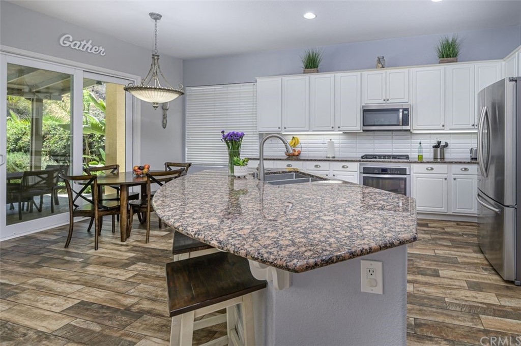 33915 Pinehurst Drive Yucaipa, CA 92399 - Photo 10 of 33 a kitchen with stainless steel appliances granite countertop a stove top oven a sink dishwasher a dining table and chairs with wooden floor
