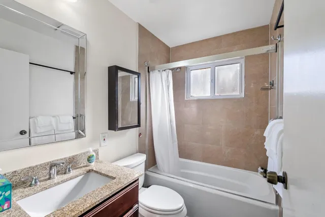 a bathroom with a granite countertop sink toilet and shower