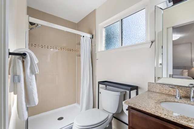 a bathroom with a granite countertop sink toilet and shower