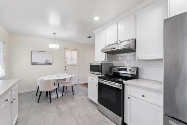 a kitchen with granite countertop a sink a counter space stainless steel appliances and cabinets