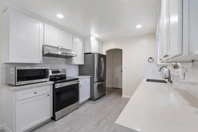 a kitchen with stainless steel appliances granite countertop a sink a stove a refrigerator and cabinets