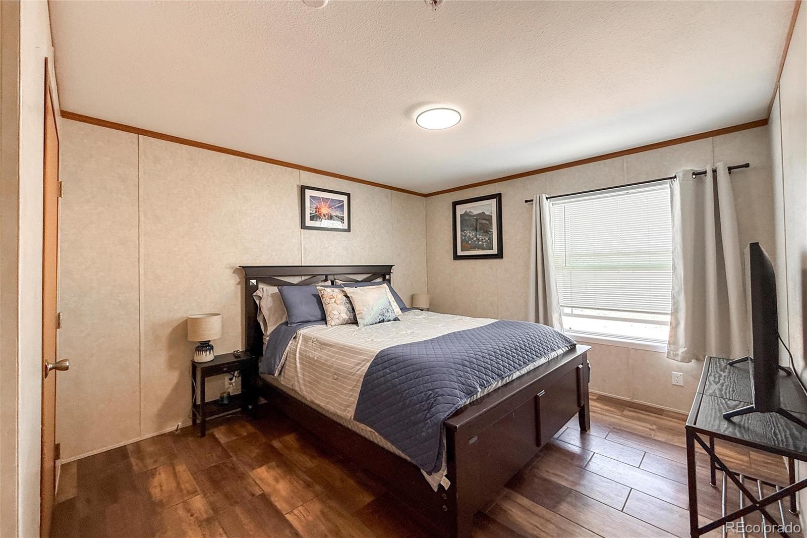 16412 Higgins Avenue Fort Lupton, CO 80621 - Photo 18 of 27 a bedroom with a bed and a flat screen tv