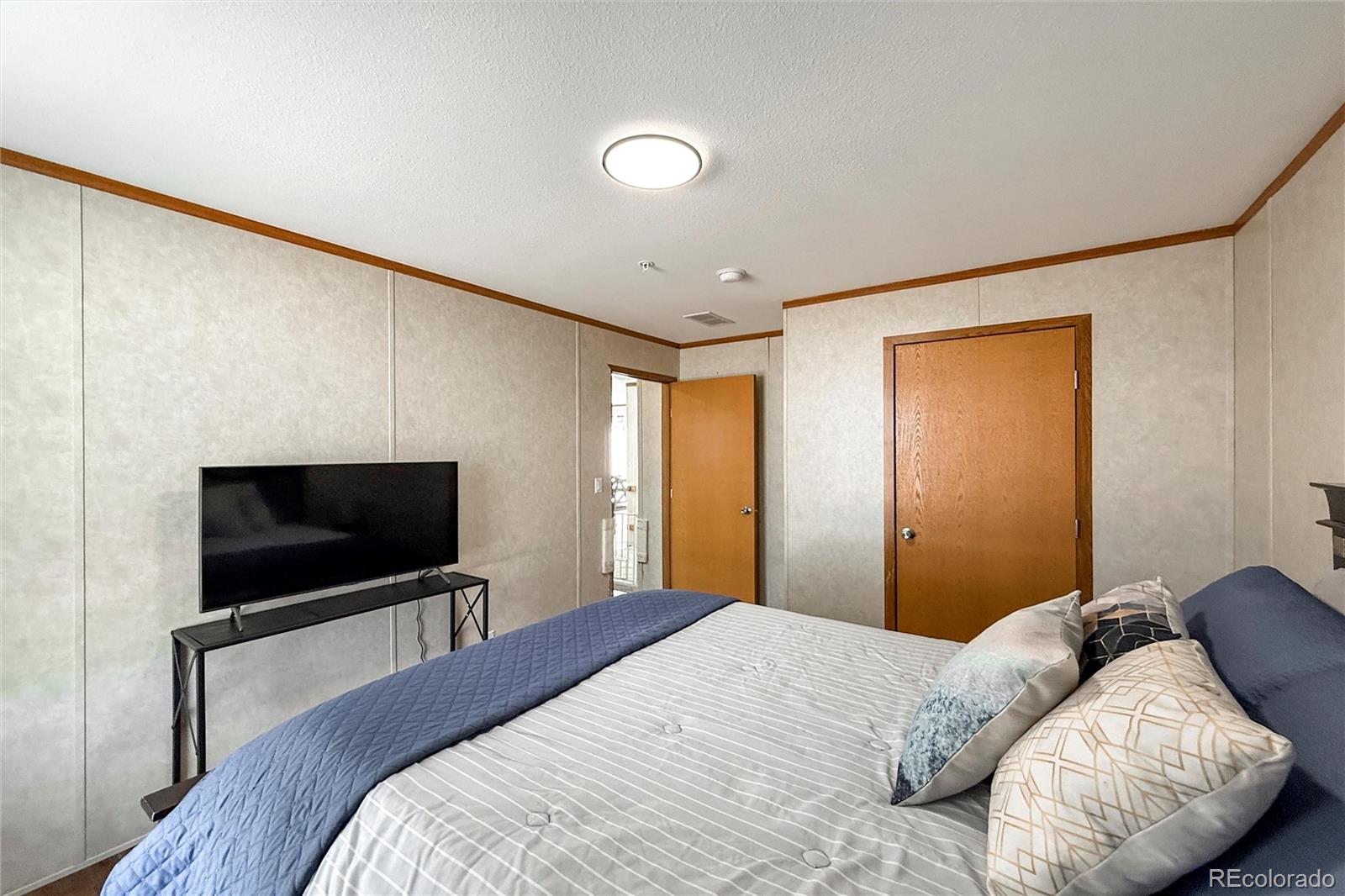 16412 Higgins Avenue Fort Lupton, CO 80621 - Photo 19 of 27 a bedroom with a bed and a flat screen tv
