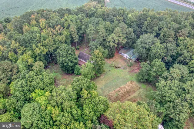 an aerial view of residential house with outdoor space and trees all around
