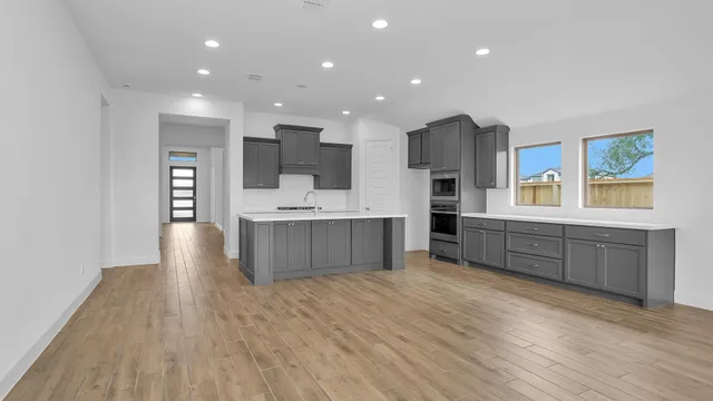 a large kitchen with stainless steel appliances kitchen island granite countertop a large counter top and wooden floors