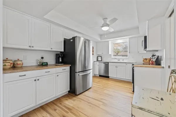 a kitchen with stainless steel appliances granite countertop a refrigerator sink and white cabinets