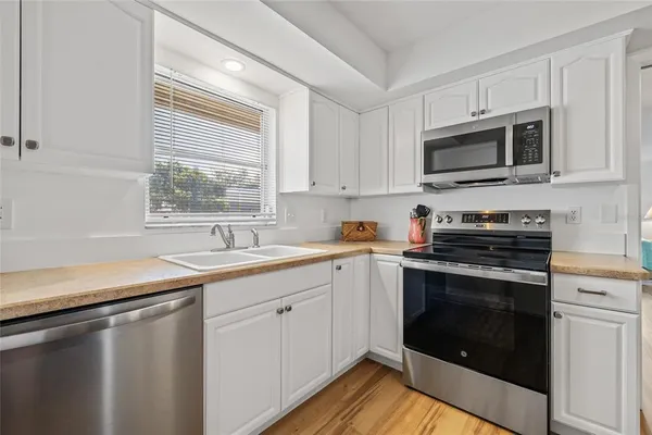 a kitchen with stainless steel appliances a stove sink microwave and window