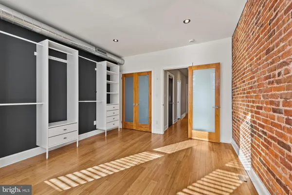 a view of an empty room with wooden floor and a bathroom