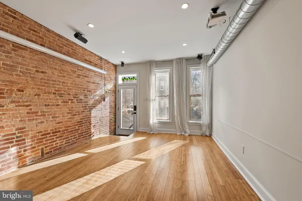a view of a hallway with wooden floor and a bathroom